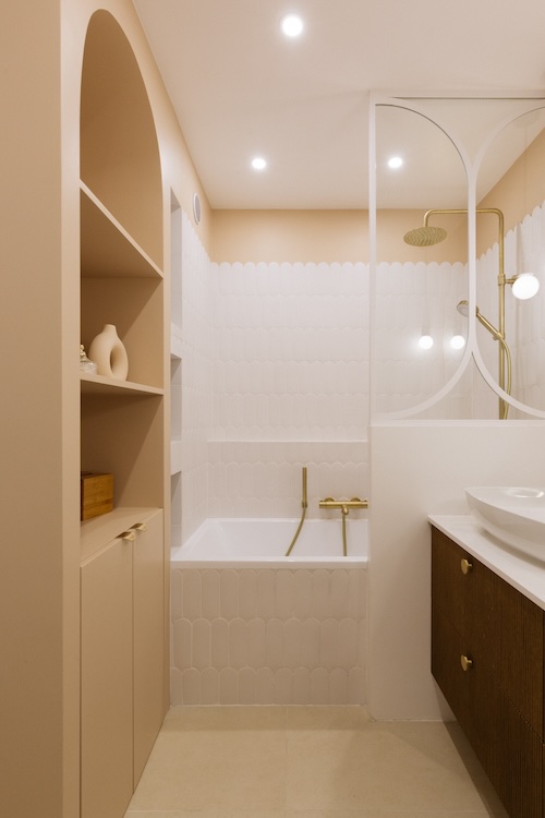 salle de bains beige et blanc, avec un pare-bain maçonné surmonté d'une verrière blanche